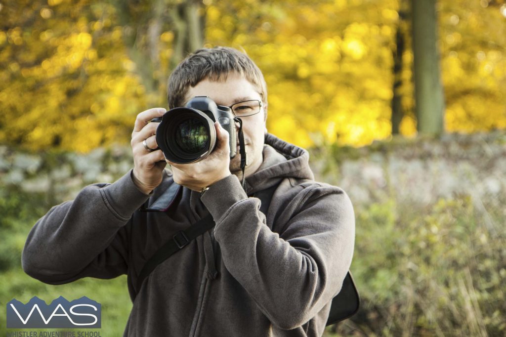 Man taking picture in the autumn park